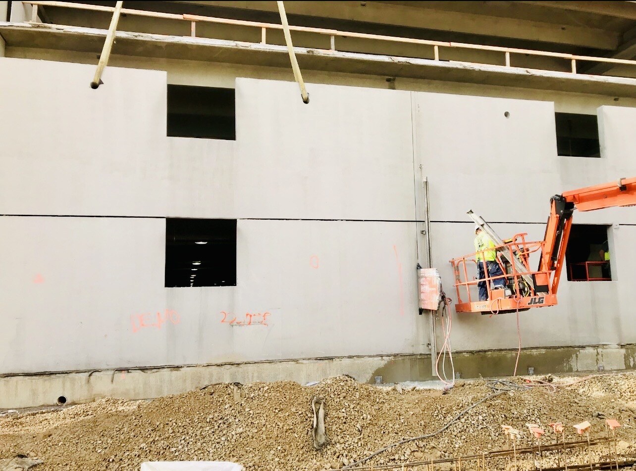 Worker sawcutting a concrete wall from an elevated work platform