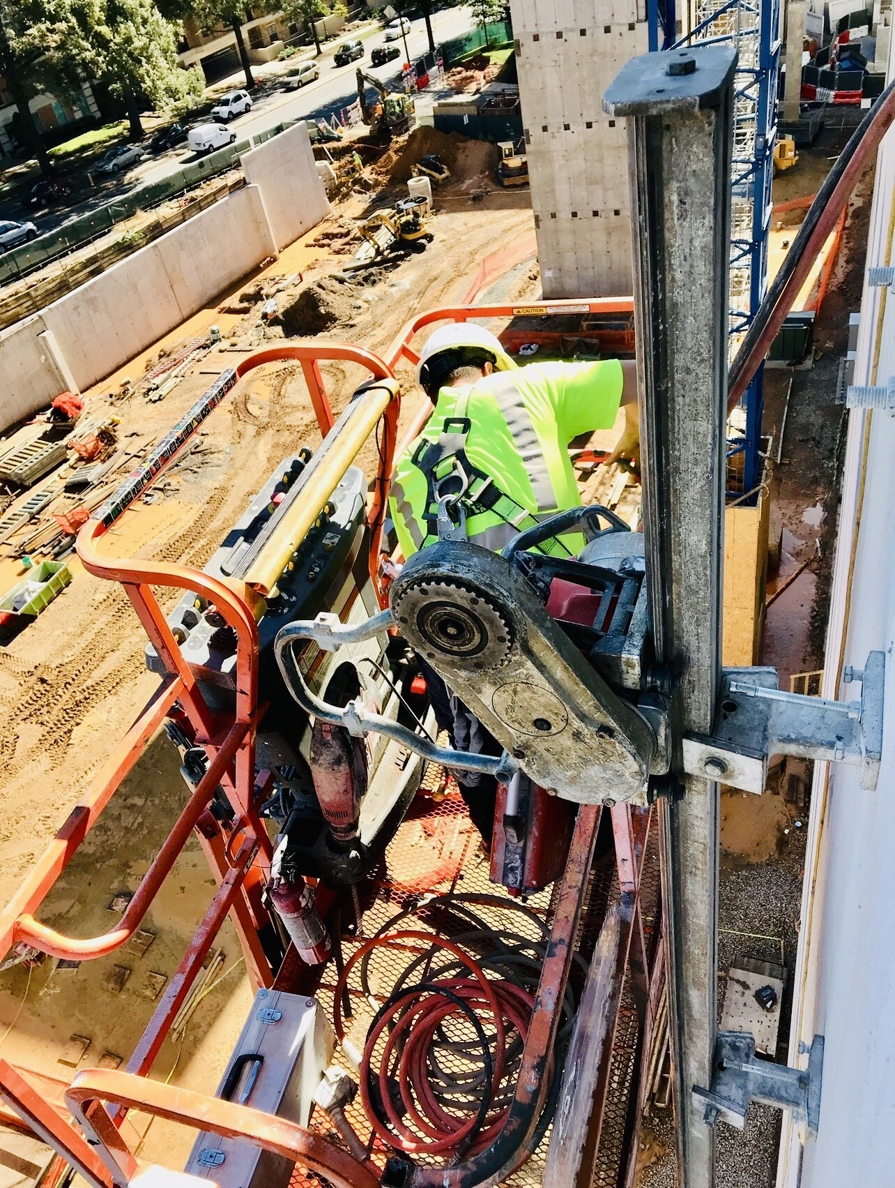 Harnessed worker using a wall saw from an elevated work platform